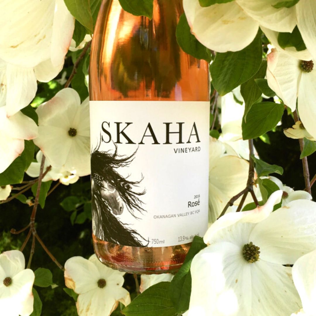 Bottle of Skaha Vineyard Rose, surrounded by white flowers 